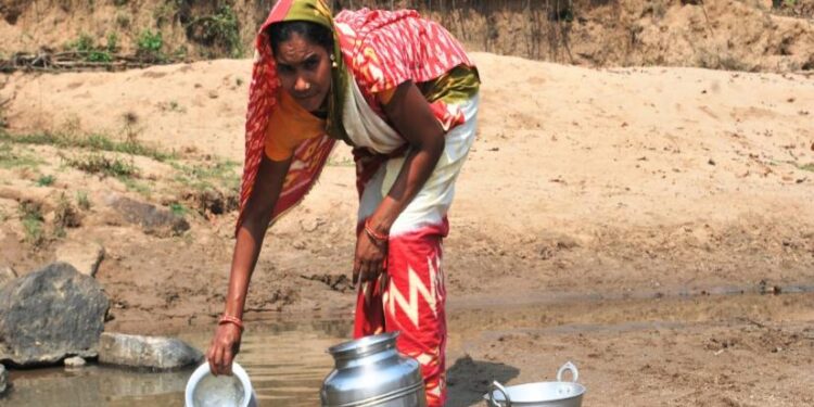 A woman from Sapari fills water from a chuan (Photo-Rajendra Hota 101Reporters)